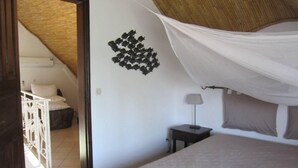 A bedroom with a bed, a nightstand, a lamp, and a wall decoration.