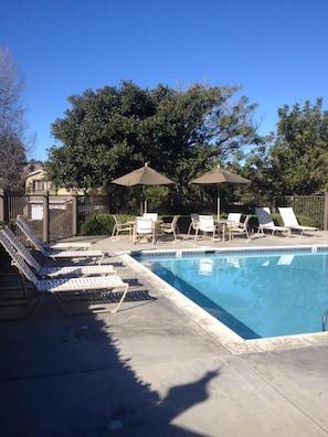 A swimming pool with lounge chairs and umbrellas, surrounded by trees and a fence. - Del Mar Heights Hideway w/ BBQ, Pool access, 5min drive to Beaches, 20min to Zoo (San Diego)