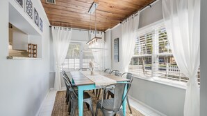A dining area with a wooden ceiling, white walls, and a view of the outdoors through large windows. - Sunny 3BR/3BA Home.  8 Houses from Beach.  Two Master Suites. (Holmes Beach)