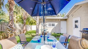 An outdoor patio with a table set for two, a grill, and a large umbrella. - Sunny 3BR/3BA Home.  8 Houses from Beach.  Two Master Suites. (Holmes Beach)