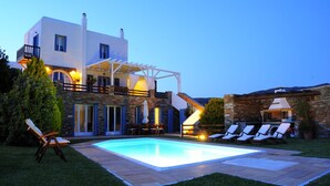 Een modern huis met een zwembad, terras en een stenen muur.