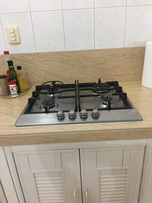 A kitchen with a gas stove, a glass container with a bottle, and a roll of paper towels on the counter. - BEROCO Front Beach House Yucatan Wi-Fi, Pool, Smart Tv (Uaymitun)