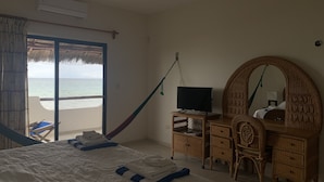 A bedroom with a bed, a TV, a dresser, and a large mirror. There is a view of the beach through the window. - BEROCO Front Beach House Yucatan Wi-Fi, Pool, Smart Tv (Uaymitun)