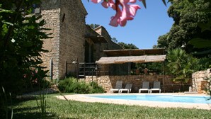 Ein Steinhaus mit Pool und Liegestühlen.