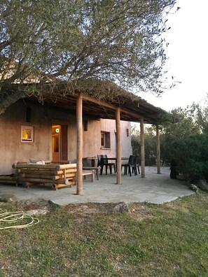 Un bâtiment rustique doté d’un patio couvert, de meubles en bois et d’une pile de bûches.