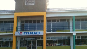 Un bâtiment à deux étages, avec une enseigne « GiantMart », de grandes fenêtres et une façade verte et jaune.