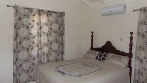 Une chambre à coucher avec un lit à baldaquin, des rideaux à motifs floraux et un ventilateur de plafond.