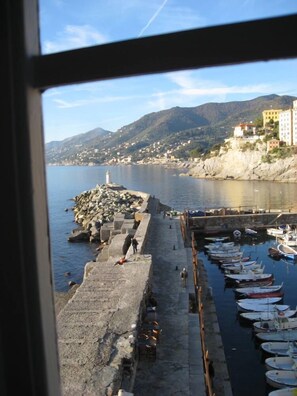 A coastal view with a stone pier, boats, and buildings on a hillside. - Camogli - Charming Apartment Right Over the Sea (Camogli)