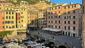 Un port où sont amarrés des bateaux, un pont de pierre et des bâtiments dotés de balcons.