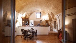 Une cuisine avec un plafond en pierre, un coin repas avec des chaises, un îlot central et un four à micro-ondes.