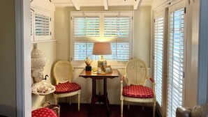 Een kamer met twee rieten stoelen met rode kussens, een kleine tafel met een lamp en zeester decoraties aan het plafond.