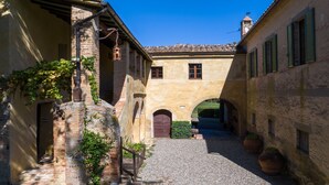 A narrow cobblestone alley with historic buildings, a stone archway, and potted plants. - Luxury Ecofriendly Country Villa  - Val d'orcia (Buonconvento Siena)