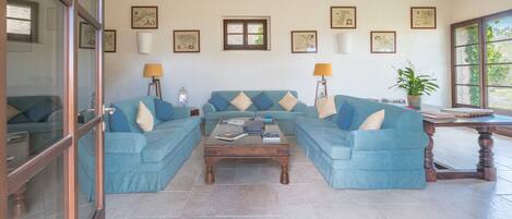 A living room with a sectional sofa, a coffee table, and wall-mounted lamps.