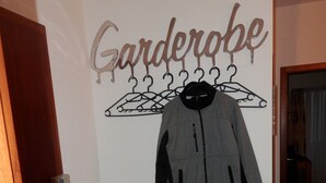 Ein Flur mit Kleiderständer, einer Jacke, einer Holztür und einer kleinen Holzbank.