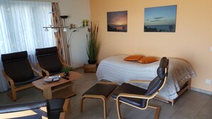 Ein gemütliches Zimmer mit einem Bett, zwei Stühlen, einem kleinen Tisch und einer Zimmerpflanze.