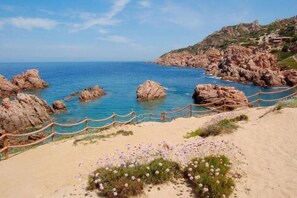 Un paisaje costero con formaciones rocosas, una playa de arena y una cerca de madera.