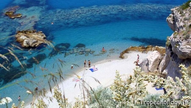 A coastal beach with clear blue waters, rocky formations, and people enjoying the beach. - APARTMENT WITH POOL (Pizzo)