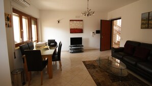 A living room with a dining area, a sofa, a TV, and a chandelier. - APARTMENT WITH POOL (Pizzo)