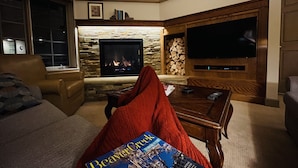 Una sala de estar acogedora con chimenea, televisión y una revista sobre la mesa auxiliar.