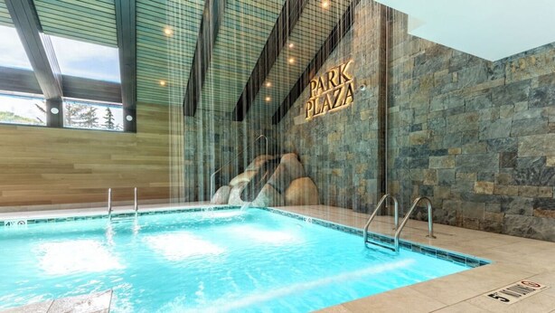 Una piscina interior moderna con un fondo de pared de piedra y un cartel que dice 'Park Plaza'.