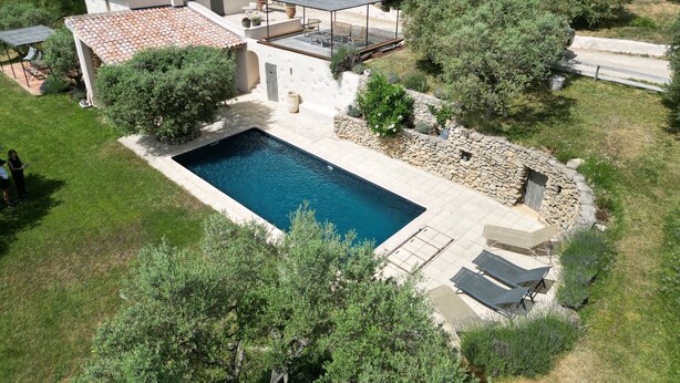 Vista aérea de una propiedad con piscina, patio amoblado y abundante vegetación.