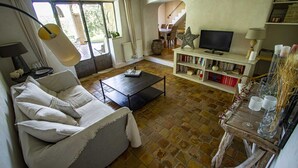 Una sala de estar con sofá, mesa de centro, televisor, estantería y un comedor con sillas y una mesa.