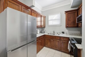 A kitchen with wooden cabinets, a stainless steel refrigerator, a granite countertop, a double sink, and a built-in oven.