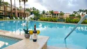 Une piscine avec des chaises longues, une bouteille de vin et des plantes tropicales.