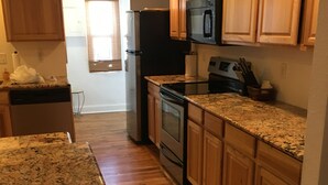 Eine Küche mit Holzausstattung, Granit-Arbeitsplatten, einem Kühlschrank, Herd, Backofen und einer Mikrowelle.