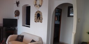 Un salon comprenant un canapé, un téléviseur et des éléments décoratifs sur les murs.