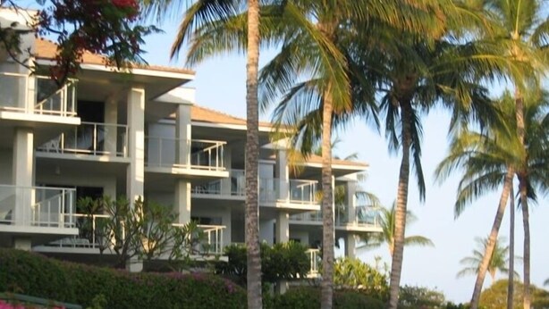 Ein mehrstöckiges Hotel mit Balkonen und Palmen.