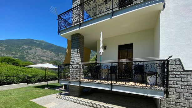 Un bâtiment à deux étages doté d’un balcon, d’une cheminée en pierre et offrant une vue sur les montagnes.