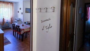 Un couloir avec, au fond, un coin repas, une porte en bois et un mur sur lequel est accroché un panneau.