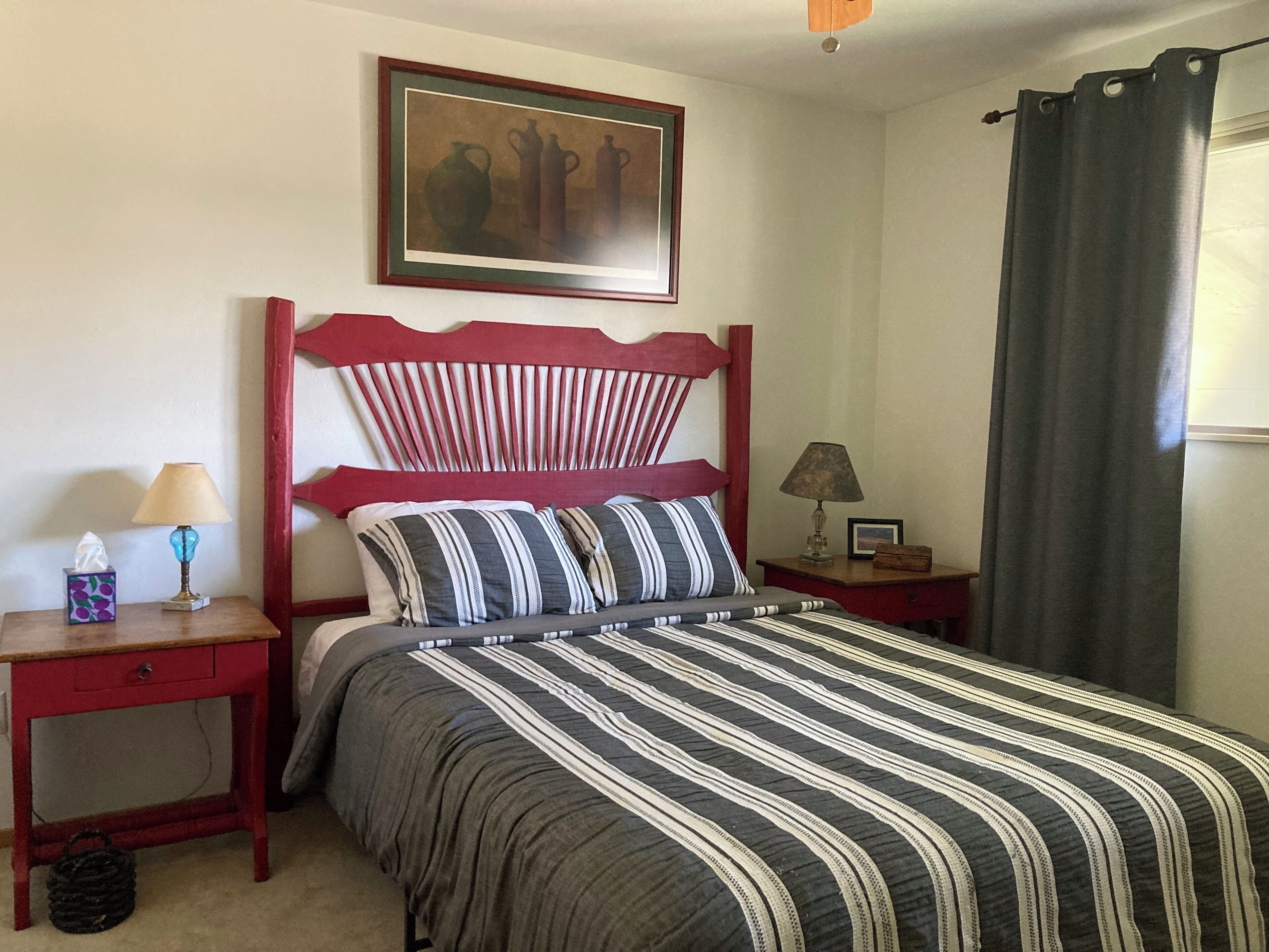 A neatly made bed with striped bedding, a wooden headboard, and a small bedside table with a lamp.