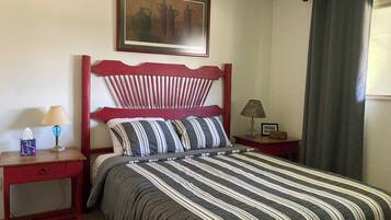 A neatly made bed with striped bedding, a wooden headboard, and a small bedside table with a lamp.