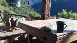 A wooden table with a black mug, set against a backdrop of mountains and a clear sky.