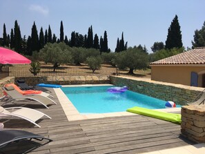 Piscina com cadeiras de descanso e parede de pedra.
