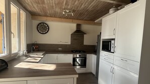 Moderni keittiö, jossa on valkoiset kaapit, puinen katto, sisäänrakennettu uuni ja mikroaaltouuni.