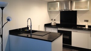 Uma cozinha moderna com bancada preta, eletrodomésticos de aço inoxidável e armários brancos.