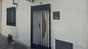 Um edifício com um portão preto, placa com o número 10 e uma pequena janela com grades.