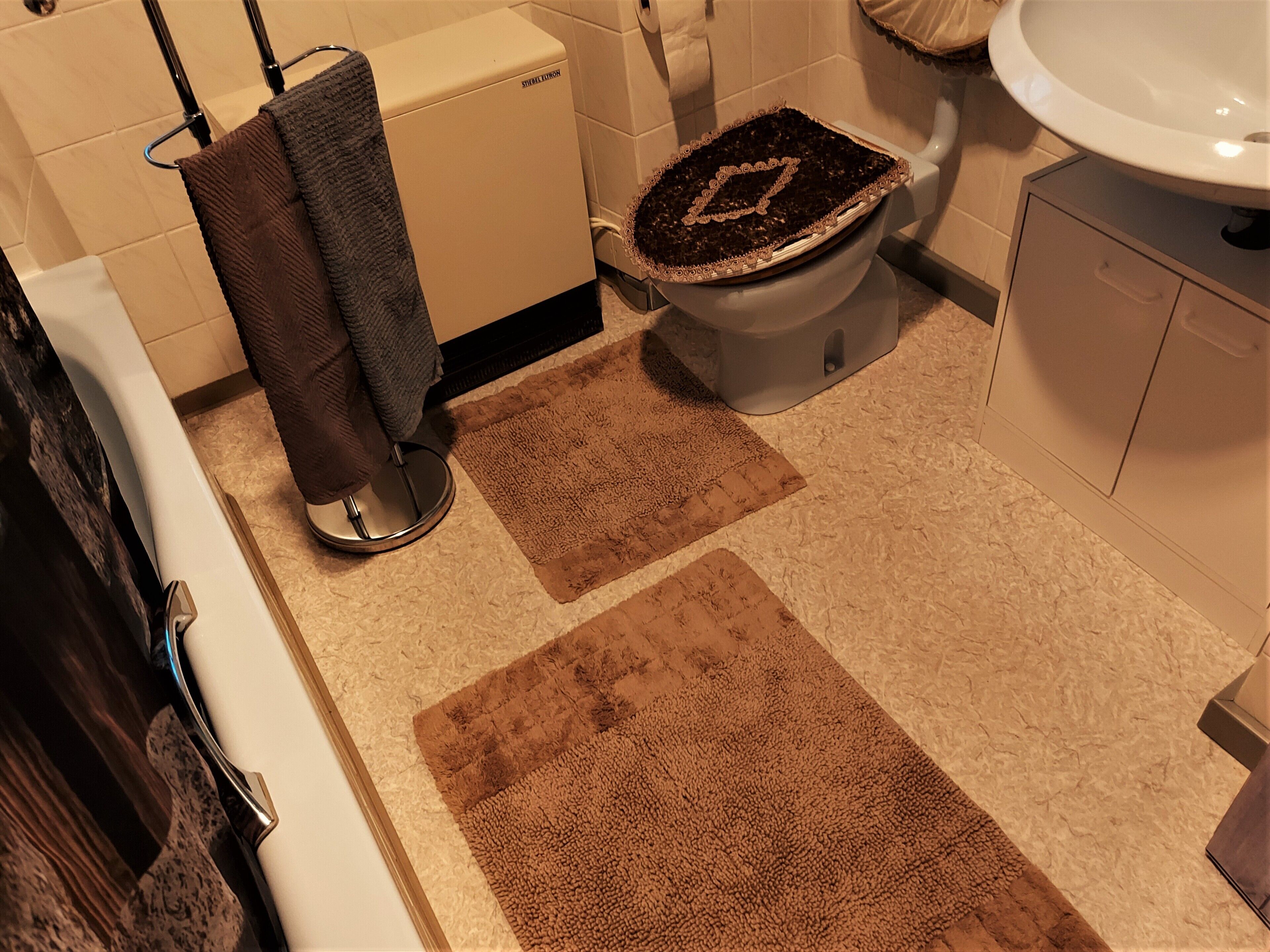 Ein Badezimmer mit Toilette, Badewanne, Waschbecken und Handtuchhalter.