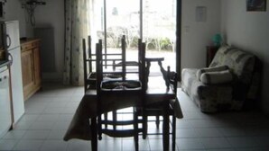 A dining area with a table and chairs, a sofa, a TV, and a view through a glass door. - Quiet chalet 5/7 places WIFI (Campan)