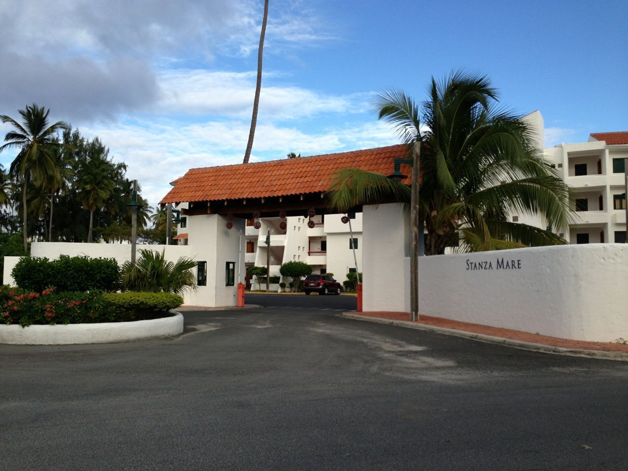 Ein Hotel mit rotem Ziegeldach, Palmen und einer weißen Wand, auf der 'Stanza Mare' steht.
