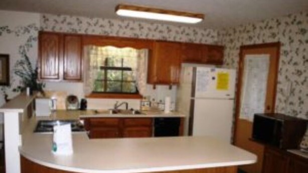 A kitchen with wooden cabinets, a white countertop, and a refrigerator. - Aunt's House-3BR 2 Bath (MAGGIE VALLEY)
