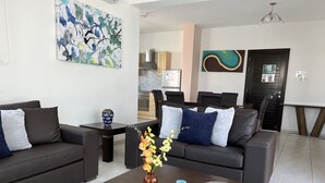 Una sala de estar moderna con sofás oscuros, una mesa de centro y un jarrón con flores.