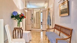 A hallway with a bench, a chair, a small table with a vase of flowers, and a framed picture on the wall. - Charming 4 bedrooms Apartment with Amazing Terrace and Fairytale Garden (Venezia)
