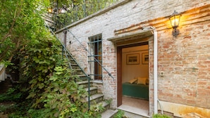 A rustic brick building with a staircase leading to a room with a bed and a green sofa. - Charming 4 bedrooms Apartment with Amazing Terrace and Fairytale Garden (Venezia)