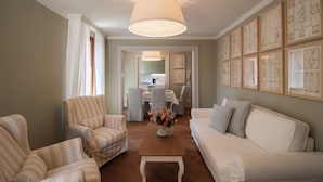 A living room with striped armchairs, a white sofa, a wooden coffee table with a floral centerpiece, and a large wall-mounted lamp. - Charming 4 bedrooms Apartment with Amazing Terrace and Fairytale Garden (Venezia)
