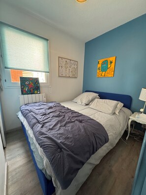 Una camera da letto con un letto, un comodino, una finestra con persiane e opere d'arte alle pareti.
