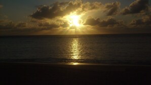 A sunset over a calm sea with clouds in the sky. - Seafront house, paradise with privacy - ITACIMIRIM - 06 bedrooms and 4 suites (Camaçari)